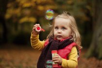 Little girl playing with bubble wand — Stock Photo