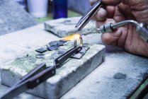 Hands of jewellery craftsman using miniature blowtorch on platinum ring — Stock Photo