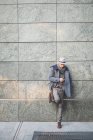 Geschäftsmann lehnt sich mit Smartphone an Wand — Stockfoto