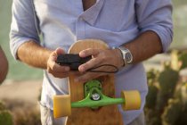 Mann hält Kamera und Skateboard in der Hand, Schnappschuss — Stockfoto