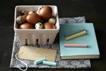 Huevos de codorniz y pollo, tiza, cuaderno, toalla de cocina - foto de stock