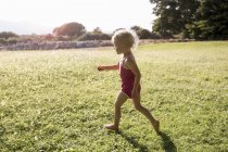 Criança feminina correndo em campo — Fotografia de Stock
