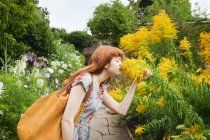 Женщина, нюхающая цветы в парке — стоковое фото
