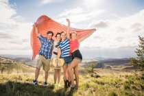 Porträt eines jungen Mannes und einer Freundin, die eine Decke auf einem windigen Hügel in Bridger, Montana, USA hochhalten — Stockfoto