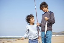 Zwei kleine Jungen, die zusammen stehen und Angelrute und Fisch halten — Stockfoto