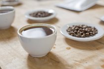 Tassen Kaffee und Bohnen auf Tellern — Stockfoto