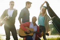 Vier erwachsene Freunde mit Akustikgitarren und Picknickdecke am Strand, dorset, uk — Stockfoto