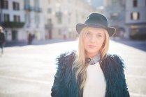 Portrait of young woman wearing fedora hat in town square — Stock Photo