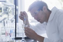 Молодий чоловічий вчений піласінг в склянку в лабораторії — стокове фото