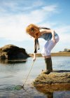 Молода дівчина риболовля в кам'яному басейні — стокове фото