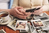 Старша жінка і онука сидять за столом, переглядаючи старі фотографії, середня секція — стокове фото