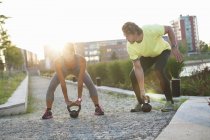 Woman and personal trainer training with kettlebells at riverside — Stock Photo