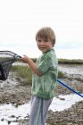 Young boy holding fishing net up — Stock Photo