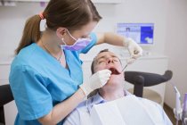 Стоматолог проводит стоматологическое обследование взрослого человека — стоковое фото