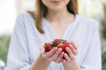 Femme avec les mains coupées tenant des fraises — Photo de stock
