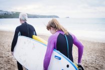 Casal com pranchas de surf andando na praia — Fotografia de Stock