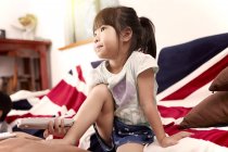 Young girl sitting on sofa watching the television at home — Stock Photo