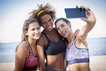 Three young women photographing themselves with phone — Stock Photo