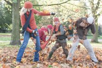 Familia tonteando en el parque, lanzando hojas de otoño - foto de stock