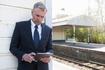 Бізнесмен використовує цифровий планшет на залізничній платформі — стокове фото