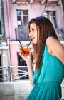 Jeune femme avec cocktail au café sur le trottoir — Photo de stock