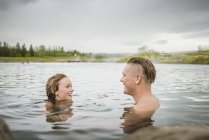 Giovane coppia sorridente che si rilassa nella sorgente termale Secret Lagoon (Gamla Laugin), Fludir, Islanda — Foto stock