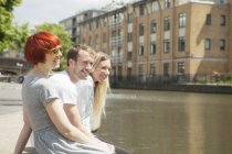 Amigos sentados al lado del canal, Londres, Reino Unido - foto de stock
