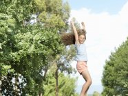Дівчина стрибає з простягнутими руками, на відкритому повітрі — стокове фото