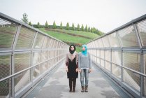 Portrait of two young female friends on park footbridge — Stock Photo