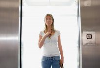 Joven mujer caucásica de pie en ascensor - foto de stock