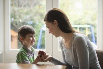 Boy smiling at mother as he hands her apple — Stock Photo
