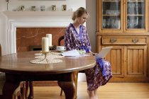 Молода жінка вдома в сукні працює на ноутбуці — стокове фото