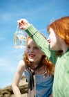 2 girls looking at fish in jar — Stock Photo