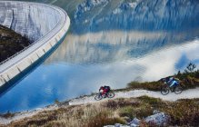 Mountain bikers por reservatório, Valais, Suíça — Fotografia de Stock
