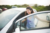 Happy woman getting into car at the coast — Stock Photo