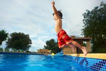 Giovane ragazzo che salta in piscina — Foto stock