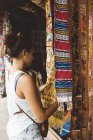 Jovem mulher comprando têxteis em market stall, Lago Atitlan, Guatemala — Fotografia de Stock
