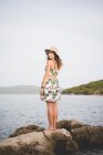Mujer de pie sobre rocas junto al mar - foto de stock