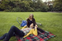Jovem casal de mãos dadas em piquenique cobertor no parque — Fotografia de Stock