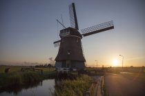 Moulin à vent et voie navigable au coucher du soleil, Vollendam, Pays-Bas — Photo de stock