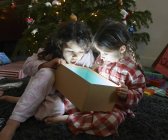 Deux enfants ouvrent la bouche sur le déballage lumineux boîte cadeau de Noël — Photo de stock