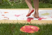 Child feet covered in paint on paper outdoors — Stock Photo