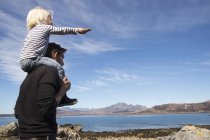 Padre que lleva a su hijo en hombros, Loch Eishort, Isla de Skye, Hébridas, Escocia - foto de stock