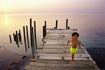Мальчик, бегущий по морю на причале на Мальдивах — стоковое фото