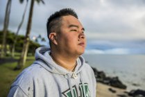 Jeune homme regardant le lever du soleil depuis la plage de Kaaawa, Oahu, Hawaï, États-Unis — Photo de stock