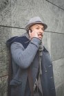 Empresário encostado à parede e falando no smartphone — Fotografia de Stock