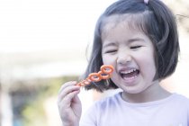 Young girl blowing bubbles, laughing, close-up — Stock Photo