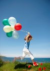 Young girl running with balloons — Stock Photo