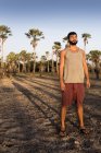 Visão frontal completa do jovem em pé na frente de palmeiras lançando sombra olhando para longe, Taiba, Ceará, Brasil — Fotografia de Stock