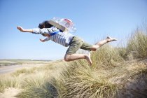 Young boy on beach, wearing fancy dress, leaping into air — Stock Photo